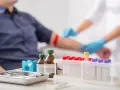Pobieranie krwi do badań, w tym do oceny odczynu Biernackiego. W tle pacjent, pielęgniarka w rękawiczkach, na pierwszym planie probówki i sprzęt medyczny.