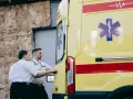 Ratownicy medyczni przy żółtej karetce z symbolem Gwiezdy Życia.