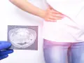 Lekarz pokazuje tomografię jamy brzusznej, sugerującą nieostre zapalenie wyrostka objawy. Pacjentka trzyma się za brzuch.