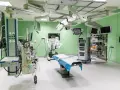 Nowoczesna sala operacyjna z robotem da Vinci, stołem zabiegowym i aparaturą medyczną.