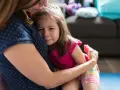 Mała dziewczynka z płaczem tuli się do mamy, wyraźnie odczuwając lęk separacyjny.