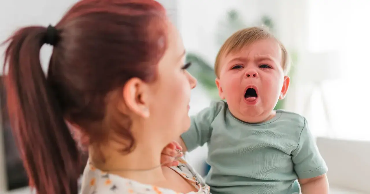 Płacz dziecka z objawami RSV. Jak leczyć? Matka tuli chore dziecko, szukając pomocy.