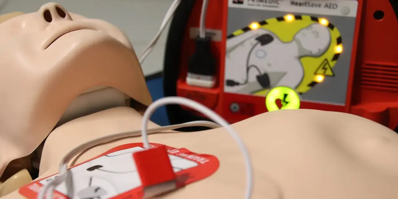 Manekin do resuscytacji z podłączonym defibrylatorem AED.