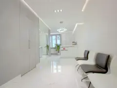 Nowoczesne wnętrze poczekalni kliniki estetycznej z białym recepcjonistą i wygodnymi fotelami.