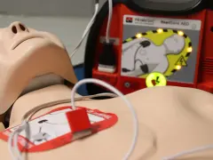 Manekin do resuscytacji z podłączonym defibrylatorem AED.