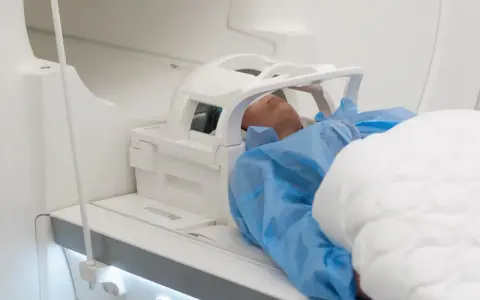 Pacjent leży w aparacie do rezonansu magnetycznego. Czas badania, czyli ile trwa rezonans głowy, zależy od wielu czynników.