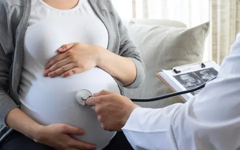 Lekarz osłuchuje brzuch ciężarnej, analizując wyniki badań USG. W trosce o zdrowie dziecka, wyklucza się m.in. cytomegalię.