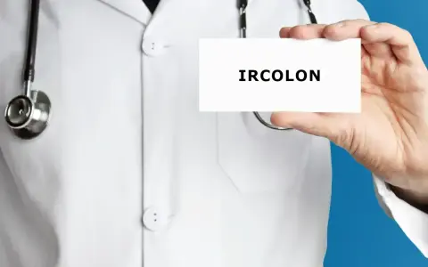 Lekarz w białym kitlu trzyma kartkę z napisem "IRCOLON". Stetoskop wisi na jego szyi.