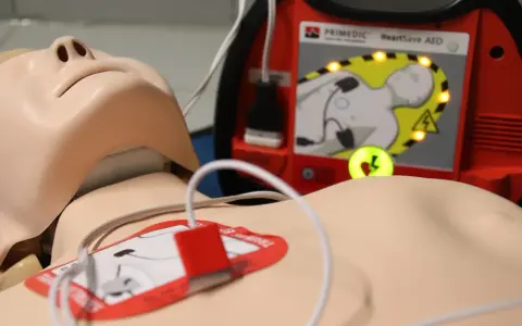 Manekin do resuscytacji z podłączonym defibrylatorem AED.