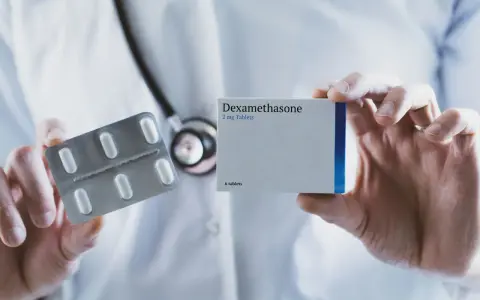 Lekarz prezentuje opakowanie leku Dexamethasone 2 mg oraz blister z tabletkami.