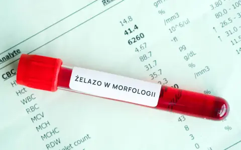 Czerwona probówka z krwią na tle wyników morfologii krwi z oznaczeniem "Żelazo w morfologii".