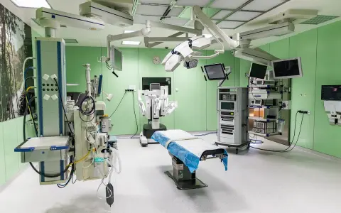 Nowoczesna sala operacyjna z robotem da Vinci, stołem zabiegowym i aparaturą medyczną.