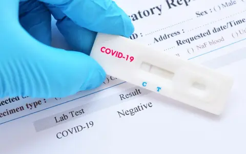 Rękawiczka w niebieskiej rękawiczce trzyma test na COVID-19 z negatywnym wynikiem. Zastanawiasz się, ile kosztuje test na covid?