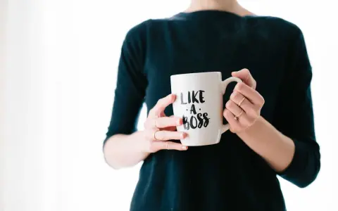 Kobieta trzyma kubek z napisem "Like a boss". Czy to pewność siebie, czy tylko maska na syndrom oszusta?