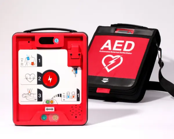 Czerwony defibrylator AED i jego czarna torba transportowa na białym tle.