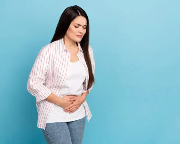 Kobieta z zamkniętymi oczami trzyma się za brzuch, cierpiąc z powodu bólu sugerującego gastroparezę.