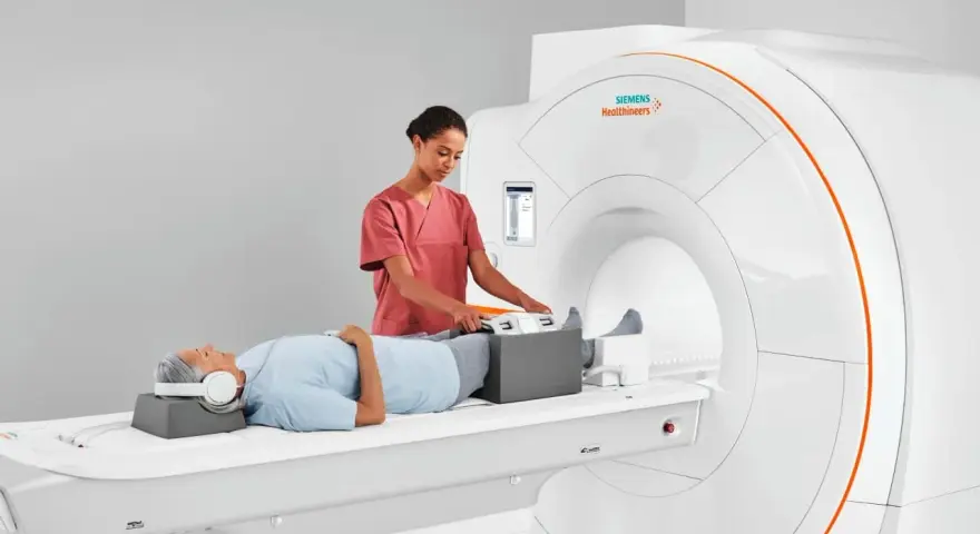 Pacjent leży na łóżku rezonansu magnetycznego, a technik przygotowuje jego nogi do badania. To właśnie mri co to za badanie, które pozwala zajrzeć do wnętrza ciała.