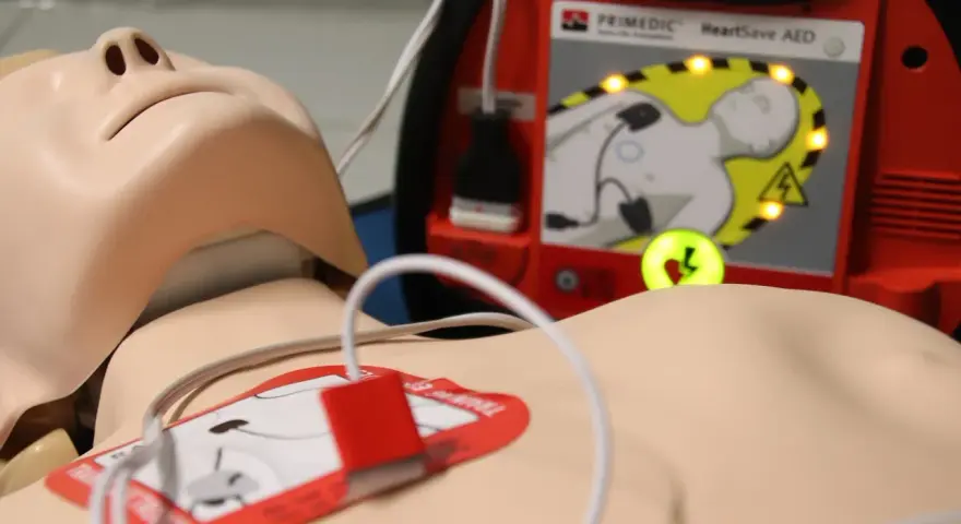 Manekin do resuscytacji z podłączonym defibrylatorem AED.