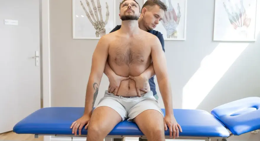 Terapeuta wykonuje terapię wisceralną, delikatnie uciskając brzuch pacjenta.