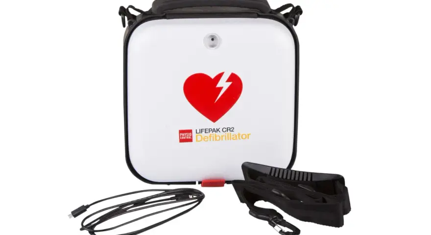 Biały defibrylator LIFEPAK CR2 z czerwonym sercem i piorunem, kablem i paskiem.