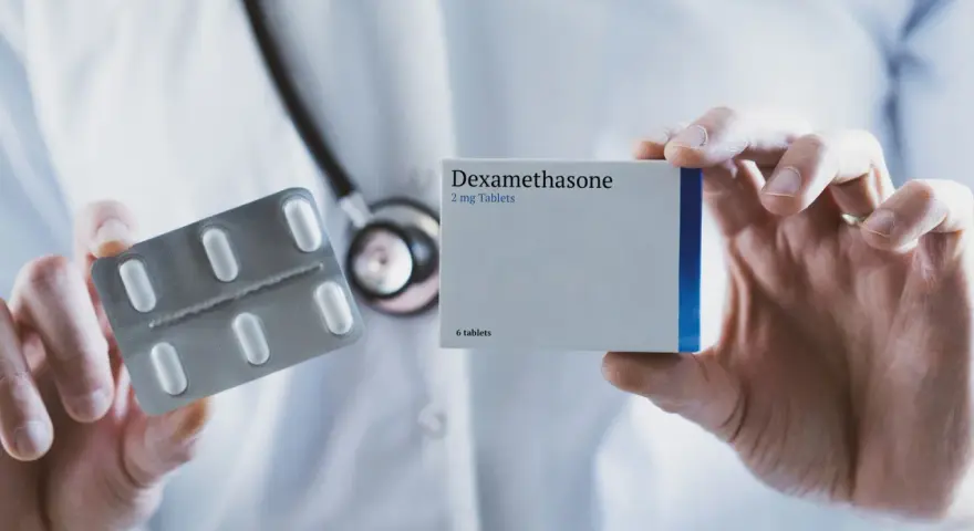 Lekarz prezentuje opakowanie leku Dexamethasone 2 mg oraz blister z tabletkami.