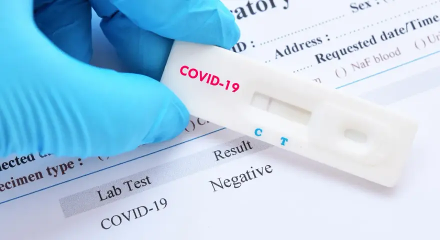 Rękawiczka w niebieskiej rękawiczce trzyma test na COVID-19 z negatywnym wynikiem. Zastanawiasz się, ile kosztuje test na covid?