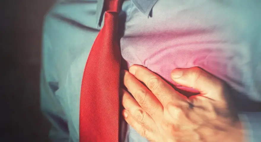Mężczyzna w czerwonym krawacie trzyma się za serce, odczuwając ból. Może to być sygnał, by zadbać o swoje concor cor.